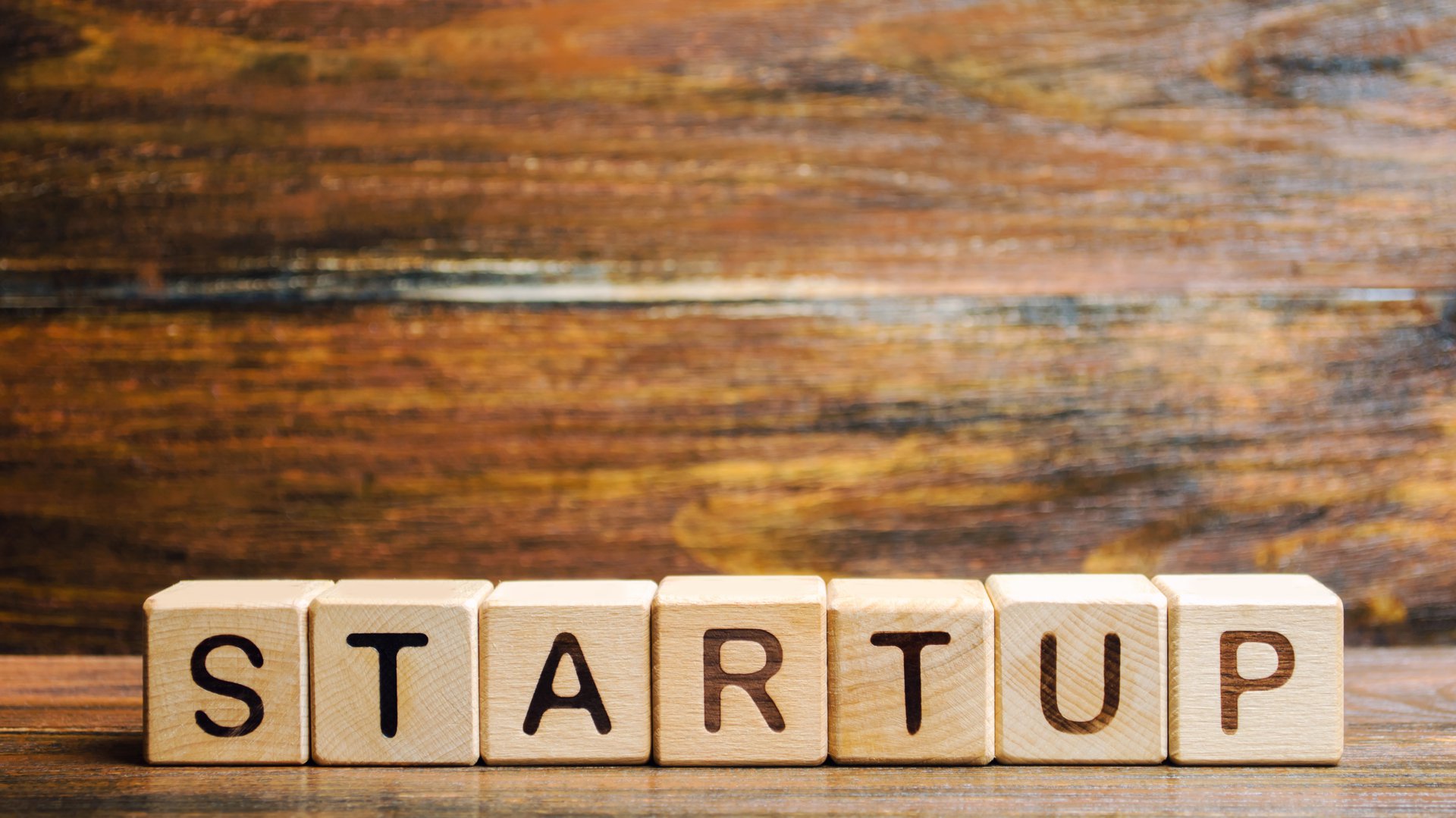Wooden blocks spelling the word "startup", representing the early-stage product a small team builds to test the market