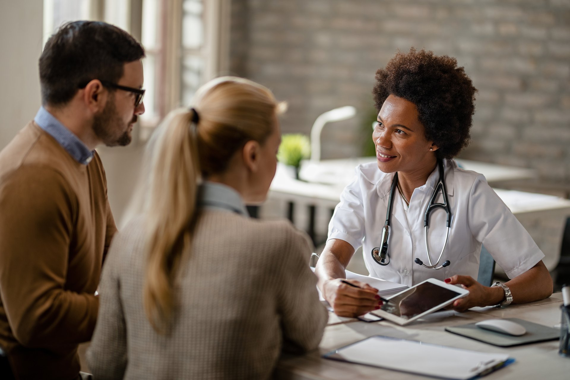 A smiling clinician using a tablet at the front desk, the staff a voice agent escalates clinical and sensitive calls to
